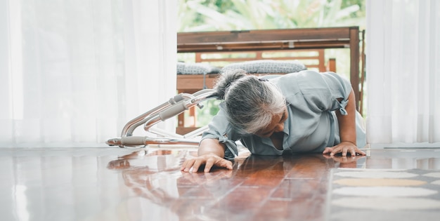 Azjatycka starsza kobieta upadła na podłogę w domu po potknięciu się na progu