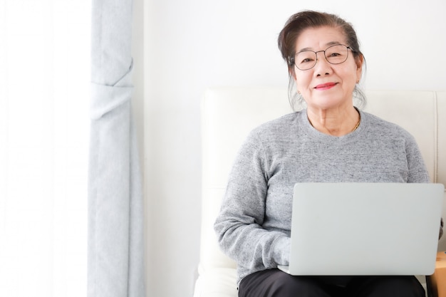 Azjatycka Starsza kobiety emerytura używać laptop w żywym pokoju