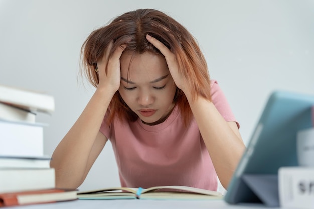 Azjatycka studentka ma niepokój z powodu egzaminów kobieta przygotowuje się do testu i uczy się lekcji w bibliotece stres rozpacz pośpiech nieporozumienie czytanie zniechęcone oczekiwanie wiedzy