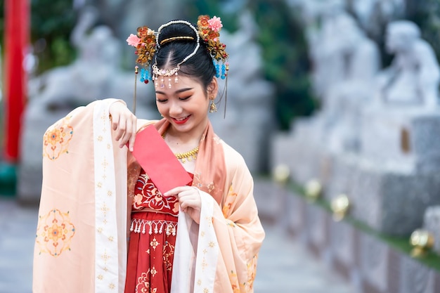 Azjatycka Szczęśliwa piękna mała dziewczynka w chińskich starożytnych strojach trzymająca czerwone koperty ozdoba na festiwal chińskiego nowego roku świętować kulturę Chin w chińskim sanktuarium Miejsca publiczne w Tajlandii