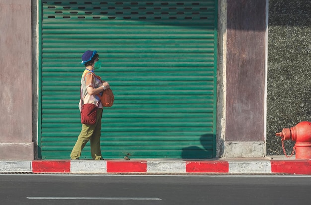 Azjatycka turystka w masce ochronnej chodzi po deptaku w mieście