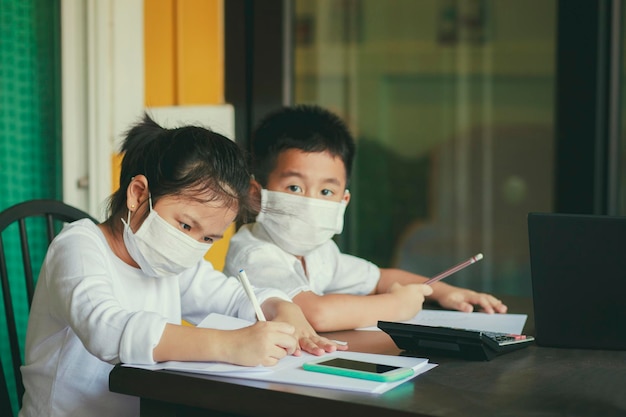 Azjatycka uczennica nosząca maskę ochronną ucząca się z komputera i smartfona