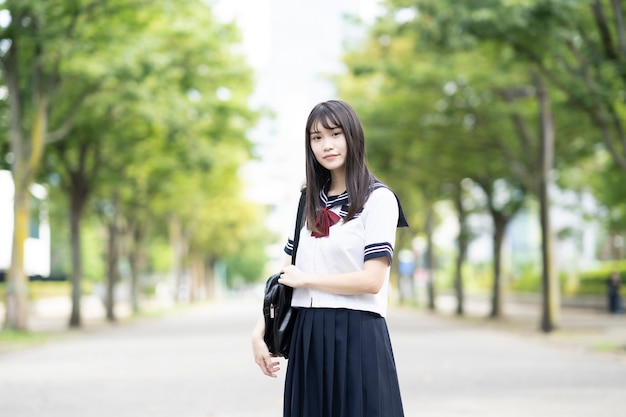 Azjatycka uczennica szkoły średniej, uśmiechając się w mundurze na zewnątrz