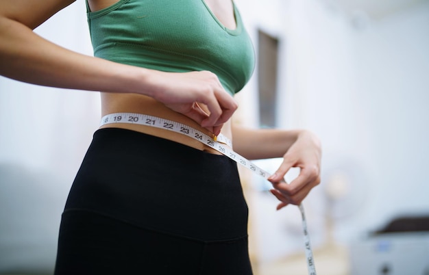 Azjatycka zdrowa kobieta odchudzanie Utrata masy ciała Szczupła kobieta pomiaru talii z taśmą miary po diecie w kontroli masy ciała w domu