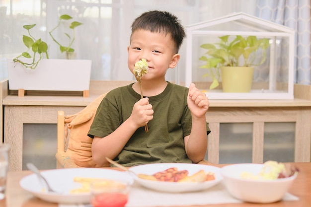 Azjatycki 5-letni chłopiec w wieku przedszkolnym dziecko je sałatka dzieciak ciesząc się wegetariańskie jedzenie Zdrowe jedzenie koncepcja zdrowego stylu życia Miękkie i selektywne skupienie