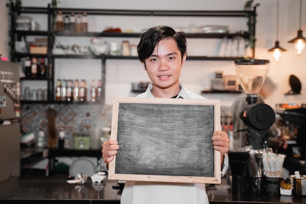 Azjatycki Barista Stoi I Trzyma Tablicę Podczas Przerwy W Pracy