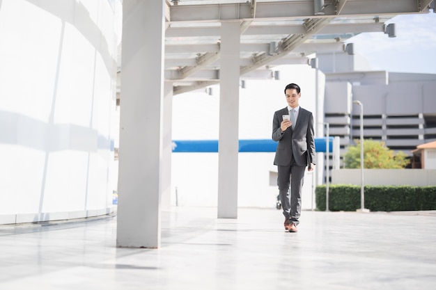 Azjatycki Biznes Człowiek Za Pomocą Inteligentnego Telefonu, Podróżowanie, Chodzenie Wewnątrz Na Lotnisku.