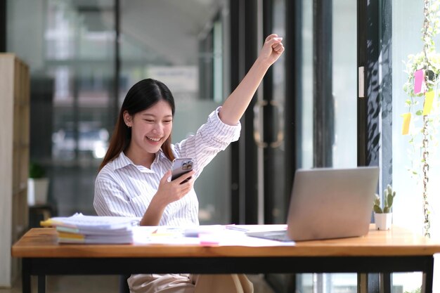 Azjatycki biznes jest podekscytowany świętowaniem sukcesu biznesowego, inspirując się doskonałymi wynikami finansowymi, które są szczęśliwe, pracując w nowoczesnym biurze na komputerze