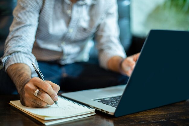 Azjatycki Biznesmen Pisz Notatki I Korzystaj Z Laptopa Do Pracy W Biurze Domowym.