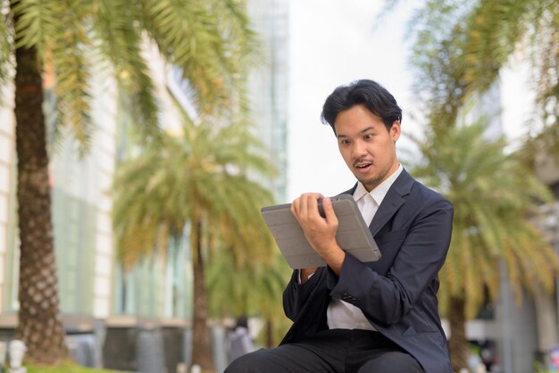 Azjatycki Biznesmen Siedzący Na Zewnątrz W Mieście Przy Użyciu Cyfrowego Tabletu