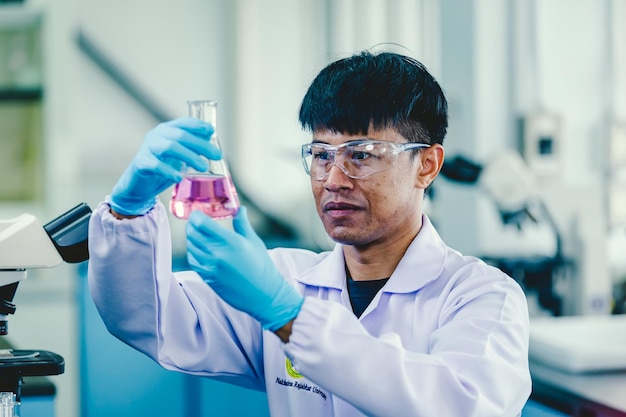 Azjatycki chemik mężczyzna w okularach i białym laboratorium pracującym w laboratorium