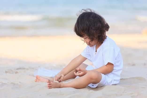 Azjatycki chłopiec bawi się na plaży w złotym słońcu
