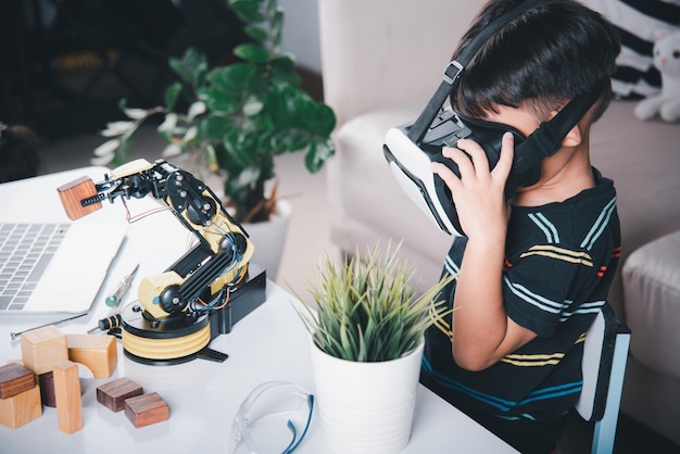 Azjatycki chłopiec używający okularów VR na ramieniu robota w warsztacie