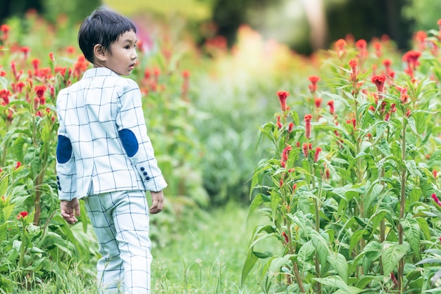Azjatycki chłopiec w wieku 5 lat w białym garniturze Spaceruj i zrelaksuj się w ogrodzie kwiatowym w parku