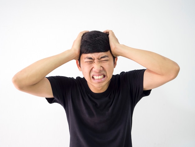 Azjatycki człowiek bardzo ból głowy dotyka głowy dwiema rękami smutną twarzą w czarnej koszuli na białym tle izolacji