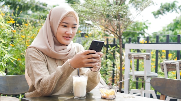 Azjatycki hidżab kobieta gra telefon w kawiarni