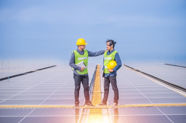 Azjatycki inżynier korzystający z tabletu sprawdzającego w systemie zasilania energią słoneczną w fabryce dachu z kontrolą ekologii przemysłowej
