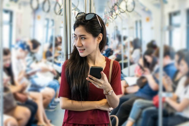 Azjatycki kobieta pasażer z przypadkowym kostiumem używać ogólnospołeczną sieć