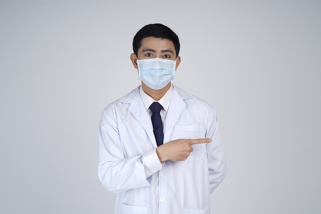 Azjatycki lekarz mężczyzna ubrany w biały fartuch i maskę medyczną