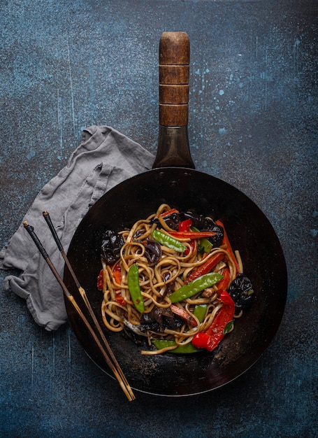 Azjatycki makaron stir fry z warzywami w czarnej patelni z woka