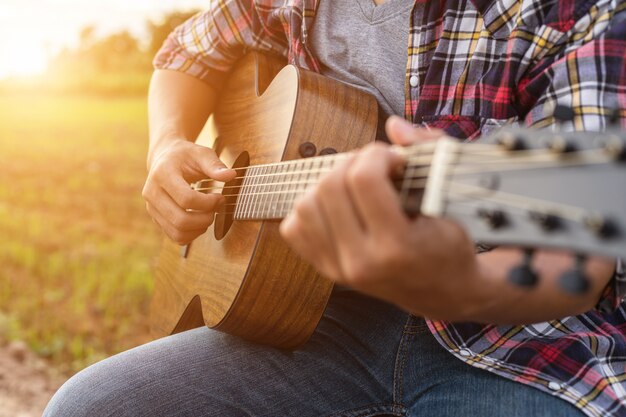 Azjatycki Mężczyzna Bawić Się Gitarę Przy Zielonym Ryżu Polem W Zmierzchu Czasie