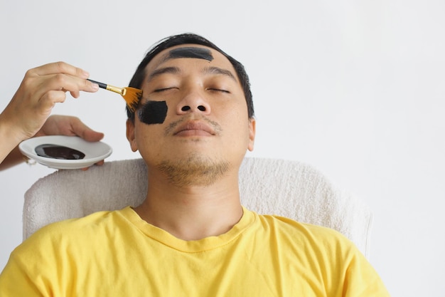 Azjatycki mężczyzna mający maskę kosmetyczną w salonie spa