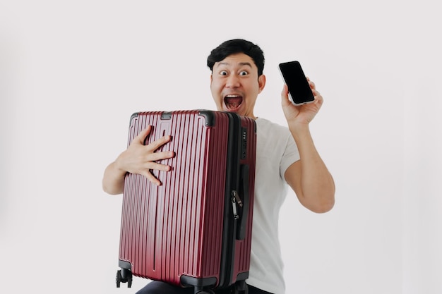 Azjatycki mężczyzna niosący walizkę i trzymający telefon komórkowy pokazujący aplikację do podróży i rezerwacji