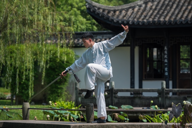 Zdjęcie azjatycki mężczyzna pracujący z mieczem tai chi rano w parku, chińskie sztuki walki