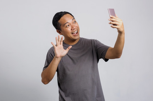 Azjatycki mężczyzna przeprowadzający rozmowę wideo z kimś przez smartfona