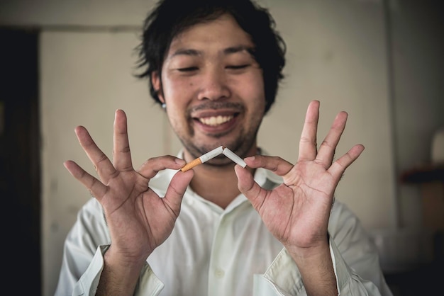 Azjatycki mężczyzna ręcznie miażdżący papierosaRzucenie koncepcji uzależnieniaBez dnia tytoniowegoBez koncepcji palenia