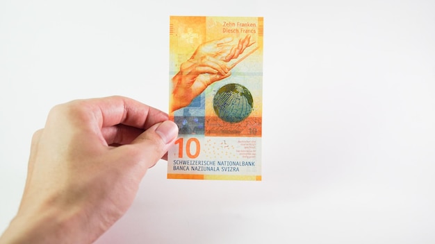Azjatycki mężczyzna ręka trzyma franka szwajcarskiego na białym tle