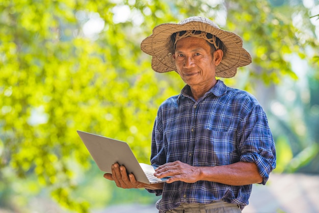 Azjatycki mężczyzna rolnik z laptopem outside
