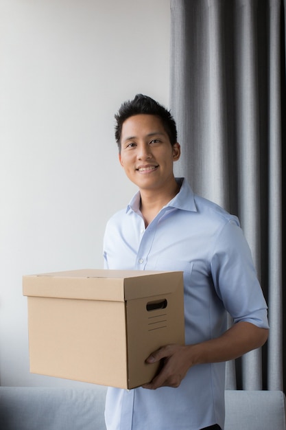 Azjatycki mężczyzna trzyma paczkę lub karton w domu