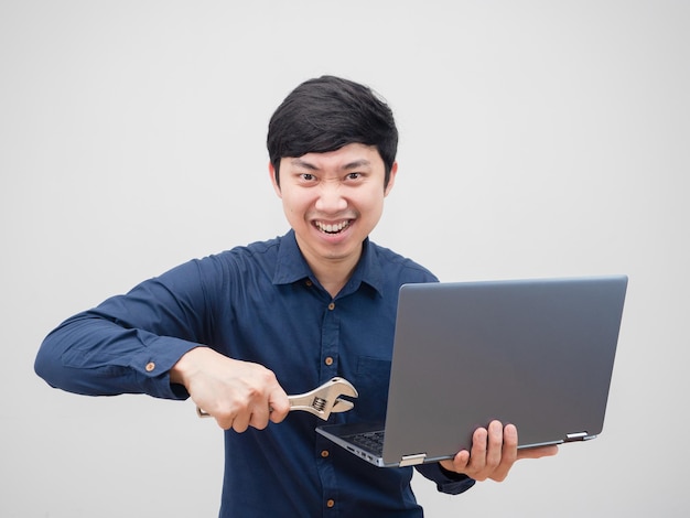 Azjatycki mężczyzna trzymający klucz nastawny naprawiony laptop w ręku pewny siebie portret twarzy