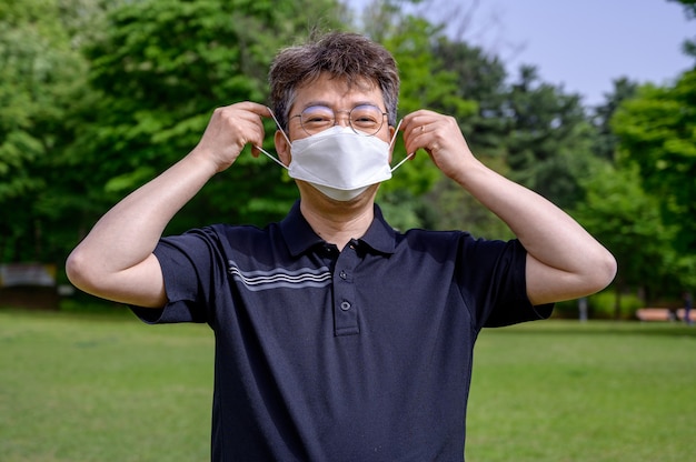 Azjatycki Mężczyzna W średnim Wieku Noszący Maskę Na Trawniku.