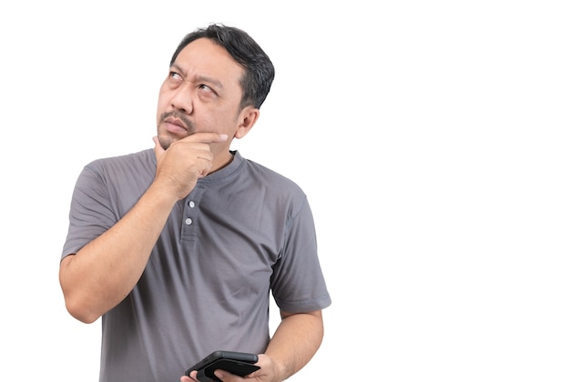 Azjatycki mężczyzna w średnim wieku trzyma inteligentny telefon i myśli na białym tle, kopia przestrzeń