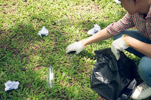 Azjatycki mężczyzna zbiera plastikowe odpady z gospodarstwa domowego w parku