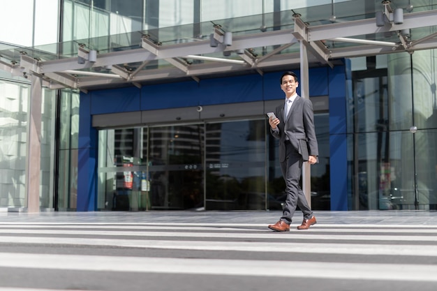 Azjatycki mężczyzna ze smartfonem idący na ulicę rozmazane tło budynku Fotografia biznesowa mody