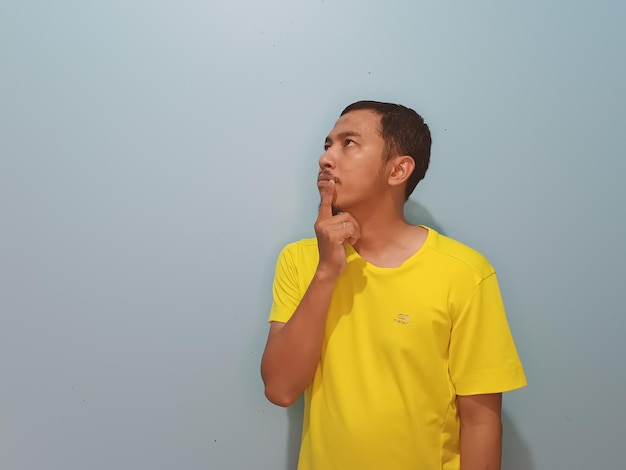Zdjęcie azjatycki mężczyzna żółta koszulka myśli myślący wyraz