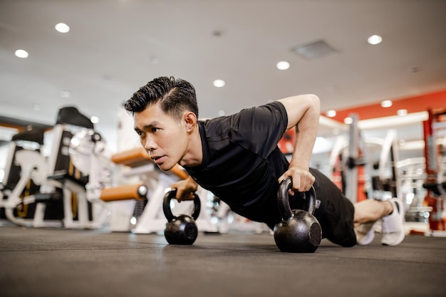 Azjatycki młody człowiek za pomocą hantle Podnoszenie ćwiczeń na siłowni na dobre zdrowe w fitness Koncepcja stylu życia i ćwiczeń sportowych