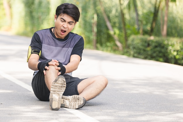 Azjatycki młody sport mężczyzna uraz kolana od jogging