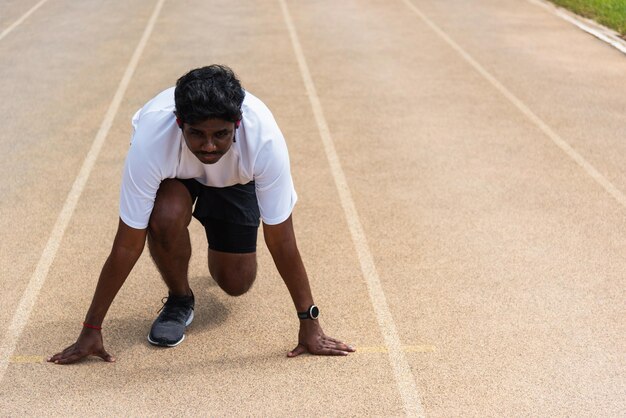 Azjatycki młody sportowiec biegacz sportowy czarny mężczyzna nosi buty do stóp aktywne, gotowe do rozpoczęcia treningu biegowego na świeżym powietrzu na bieżni, aby zrobić krok do przodu, zdrowy trening ćwiczeń, zbliżenie twarzy z przodu