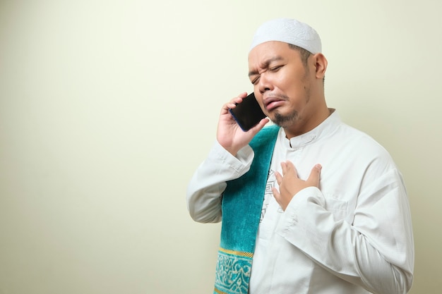 azjatycki muzułmanin wygląda na smutnego, gdy odbiera wiadomości ze swojego smartfona