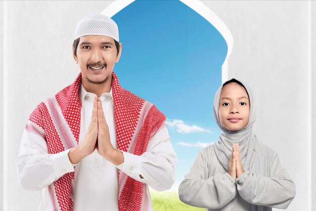 Azjatycki muzułmański mężczyzna i dziewczyna stojąc z pozdrowieniami na meczecie