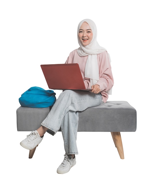 Azjatycki muzułmański student trzymając laptopa przed białym tle na białym tle