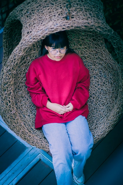 Azjatycki Nastolatek Siedzi W Bambusowej Huśtawce Na Tarasie Domu