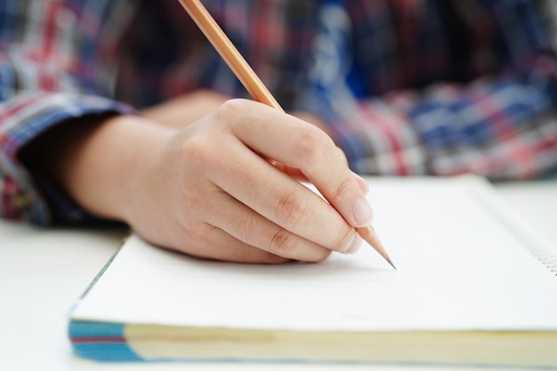 Azjatycki nastoletni uczeń pisze lekcję pracy domowej do egzaminu online