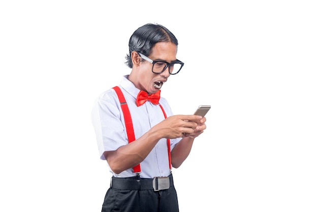 Azjatycki nerd z brzydką twarzą trzymający telefon komórkowy ze zszokowanym wyrazem twarzy na białym tle