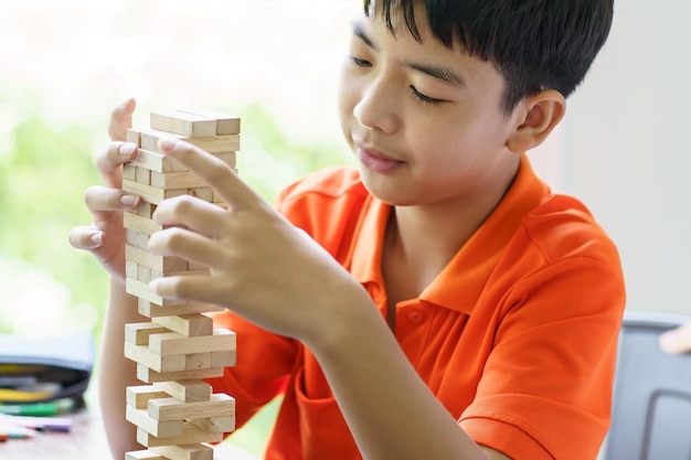 Azjatycki ojciec i syn grają w grę z drewnianymi blokami Beztroski chłopiec grający w grę ze drewnianych bloków konstruktor z bloków z ojcem w domu