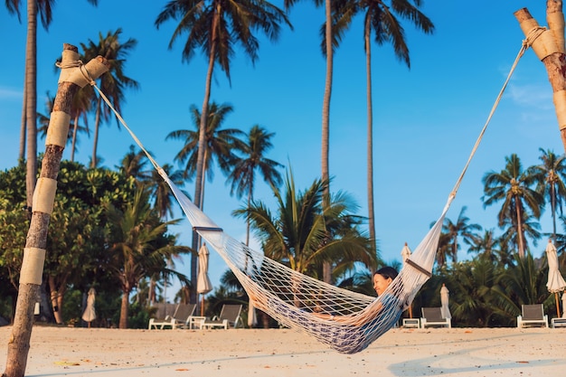 Zdjęcie azjatycki podróżnik kobieta leżąc na hamaku na plaży